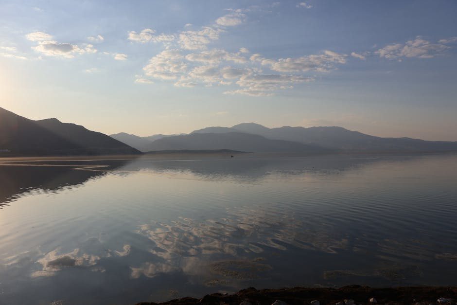Tranquil view of a serene lake reflecting mountains and sky at sunrise in Isparta, Türkiye.