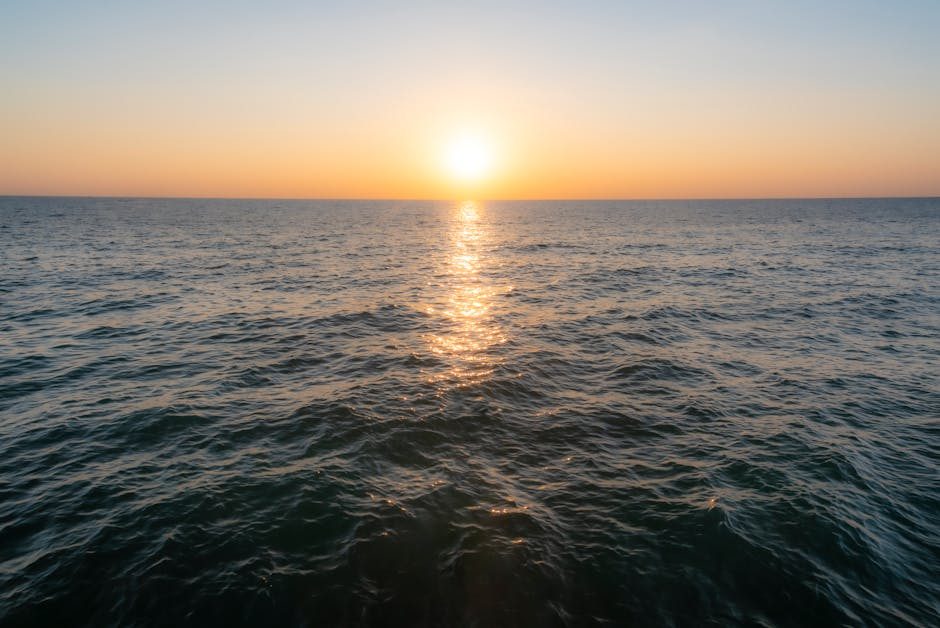 Beautiful sunset over the ocean with golden reflections on the water's surface, creating a serene seascape.