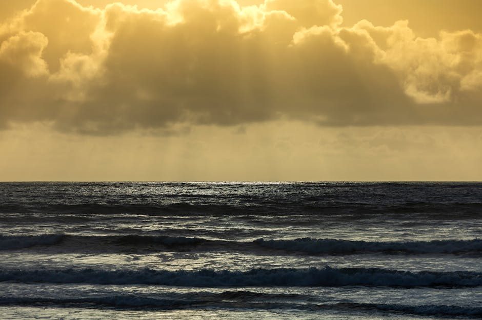 Golden sunset with dramatic clouds over ocean waves, creating a tranquil seascape.